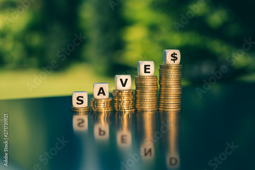 Symbol for saving or spending money. Dice form the word "save" while the word "spend" is visible in the reflection.