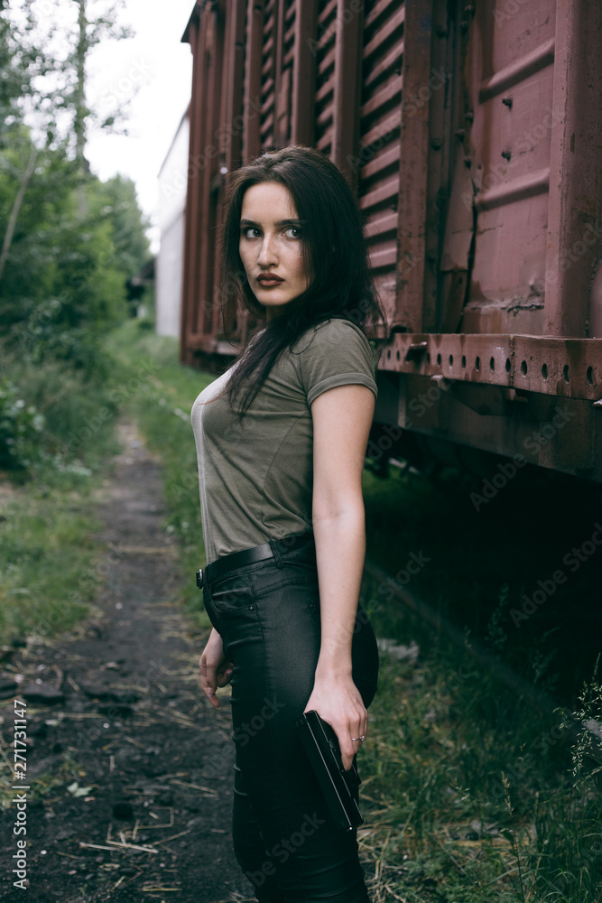 Fototapeta premium Powerful Woman Holding Gun Action Movie Style. Train adventure. Military girl with .