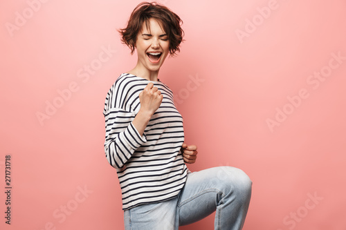 Woman posing isolated over pink wall background make winner gesture.