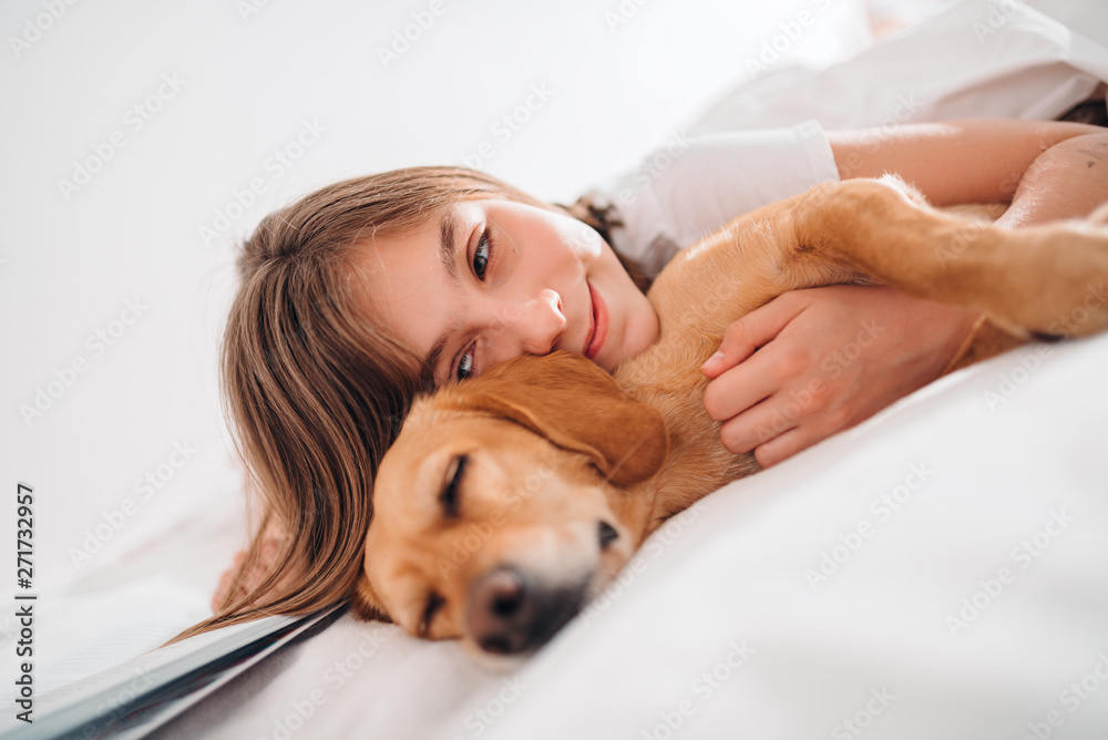 Girl embracing dog on the bed