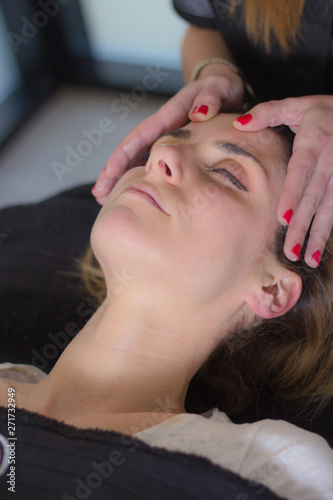 Close-up view of young woman getting facial massage treatment at beauty spa salon.