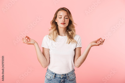 Concentrated young blonde woman posing isolated over pink wall background meditate.