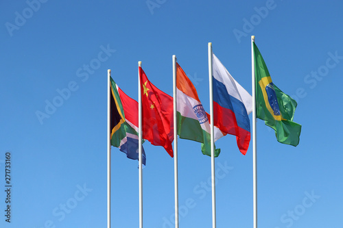 Waving flags of the BRICS countries against the clear blue sky. The summit of Brazil, Russia, India, China and South Africa