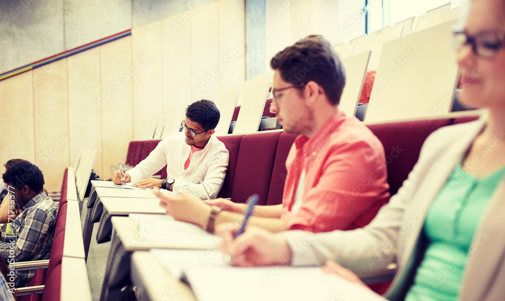education, high school, university, learning and people concept - group of international students with notebooks writing in lecture hall education, high school, university, learning and people concept - group of international students with notebooks writing in lecture hall