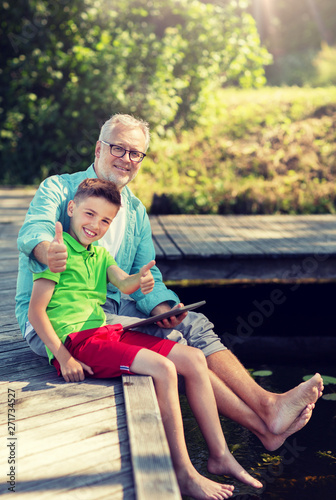 family, generation, technology, communication and people concept - grandfather and grandson with tablet pc computer sitting on river berth © Syda Productions