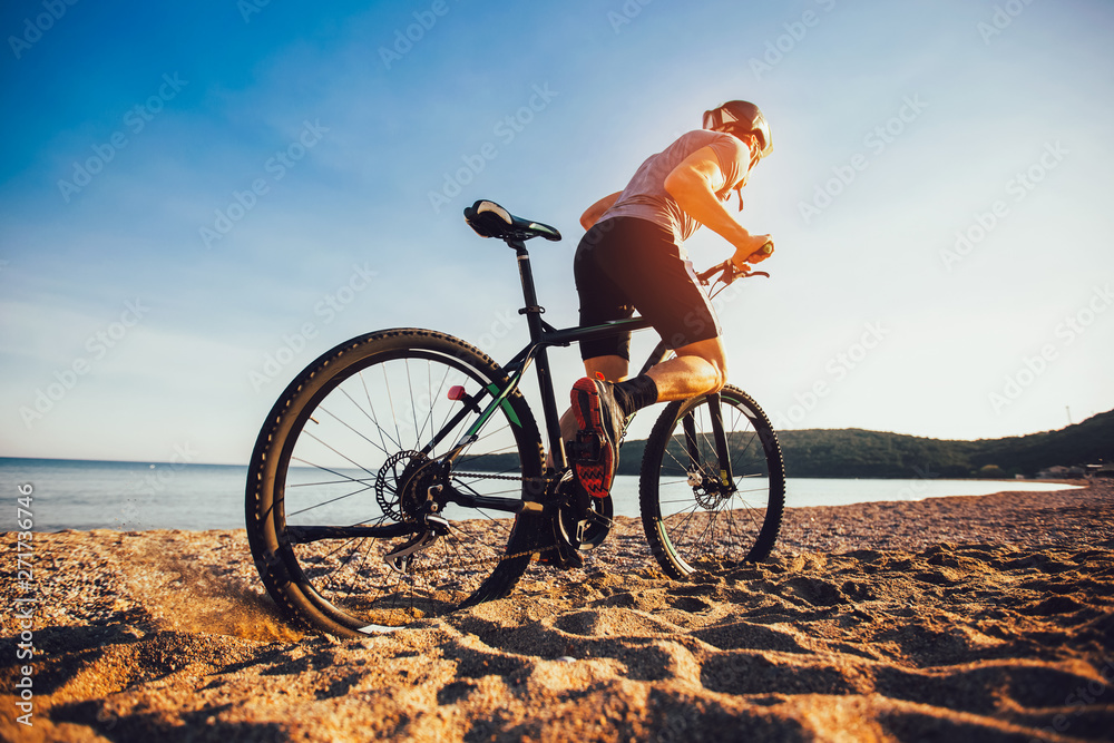 Fototapeta premium Man ride mountain bike on the beach. Sport and active life concept.