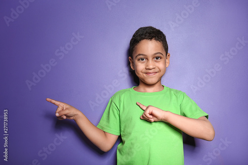 Portrait of cute little boy pointing at something on color background © Pixel-Shot
