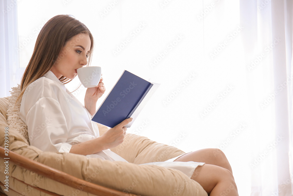 Beautiful young woman drinking coffee while reading book at home Beautiful young woman drinking coffee while reading book at home