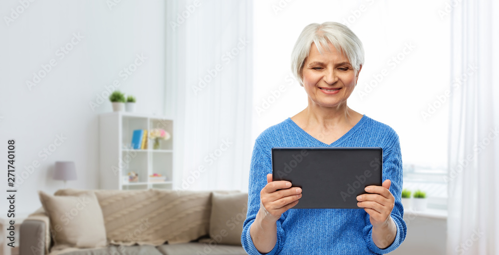 technology and old people concept - smiling senior woman using tablet computer over home living room background technology and old people concept - smiling senior woman using tablet computer over home living room background