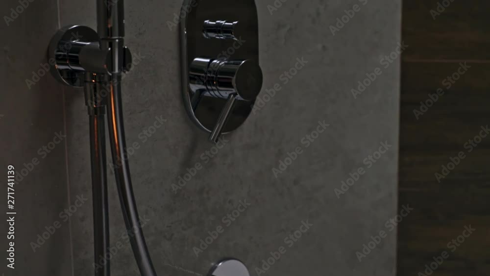 Modern chrome or stainless steel bathroom fittings mounted on a tiled