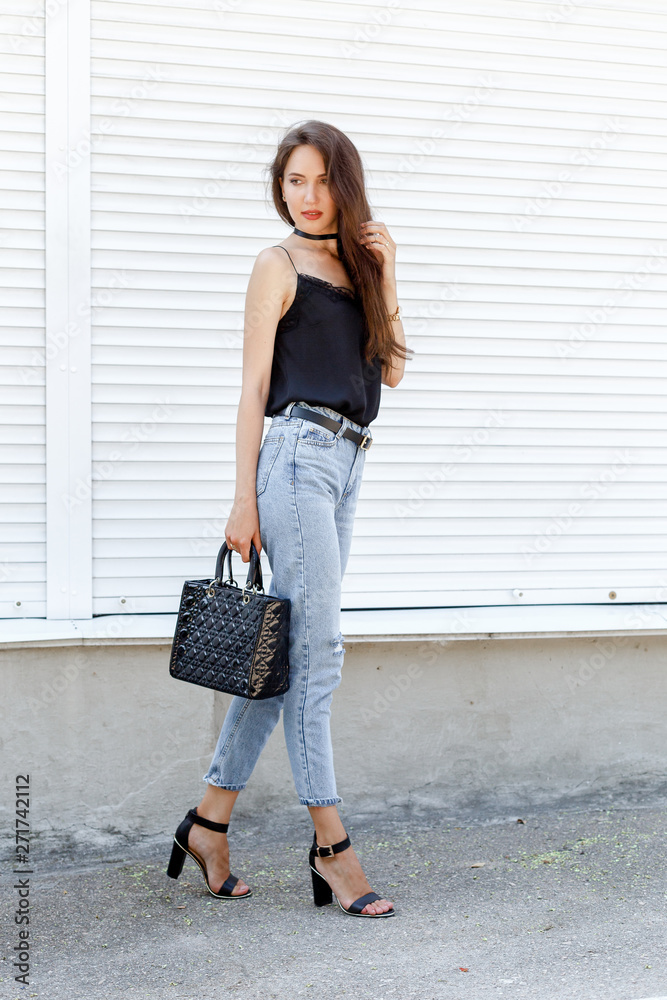 Young stylish woman wearing black cami silk top, blue cropped