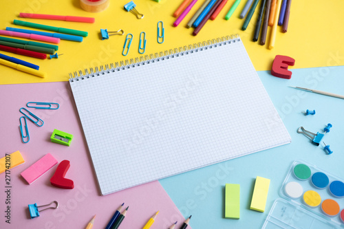 Group School supplies around a notepad on color background.