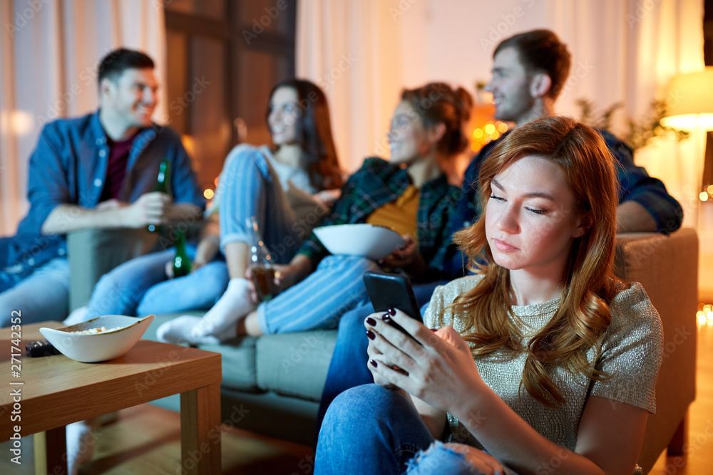 technology, internet addiction and people concept - sad young woman with smartphone at home friends party in evening technology, internet addiction and people concept - sad young woman with smartphone at home friends party in evening