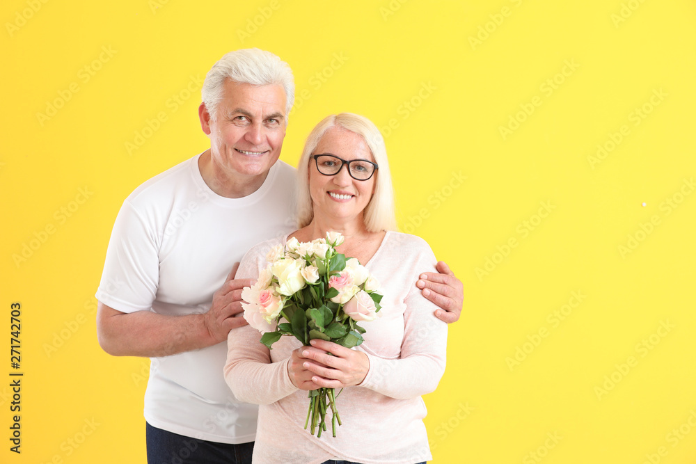 Portrait of happy mature couple with flowers on color background Portrait of happy mature couple with flowers on color background