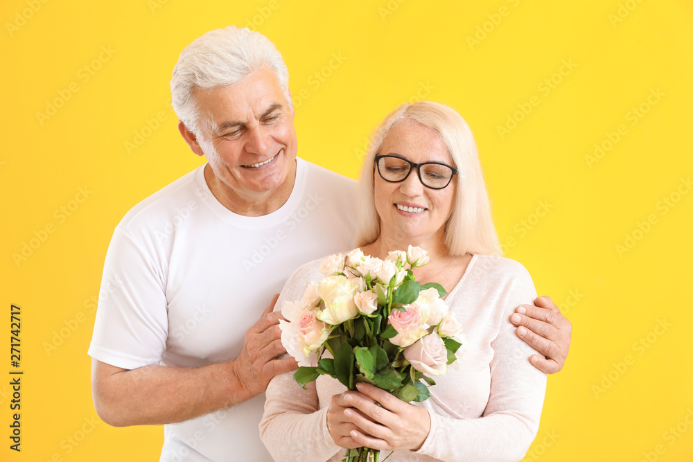 Portrait of happy mature couple with flowers on color background Portrait of happy mature couple with flowers on color background
