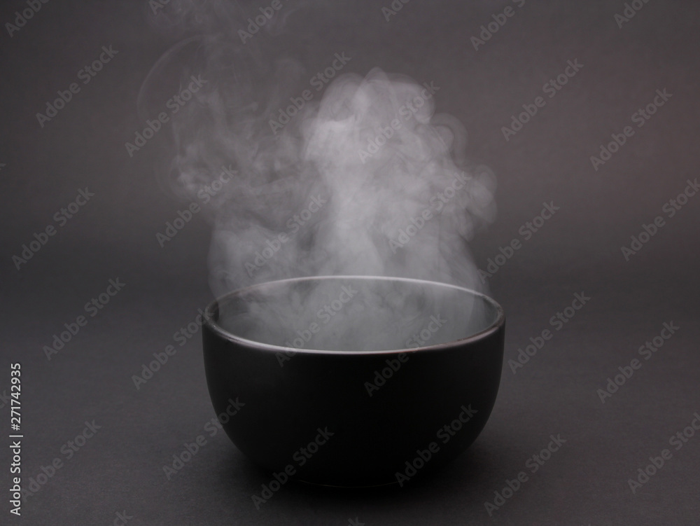 Bowl of hot soup on black background 