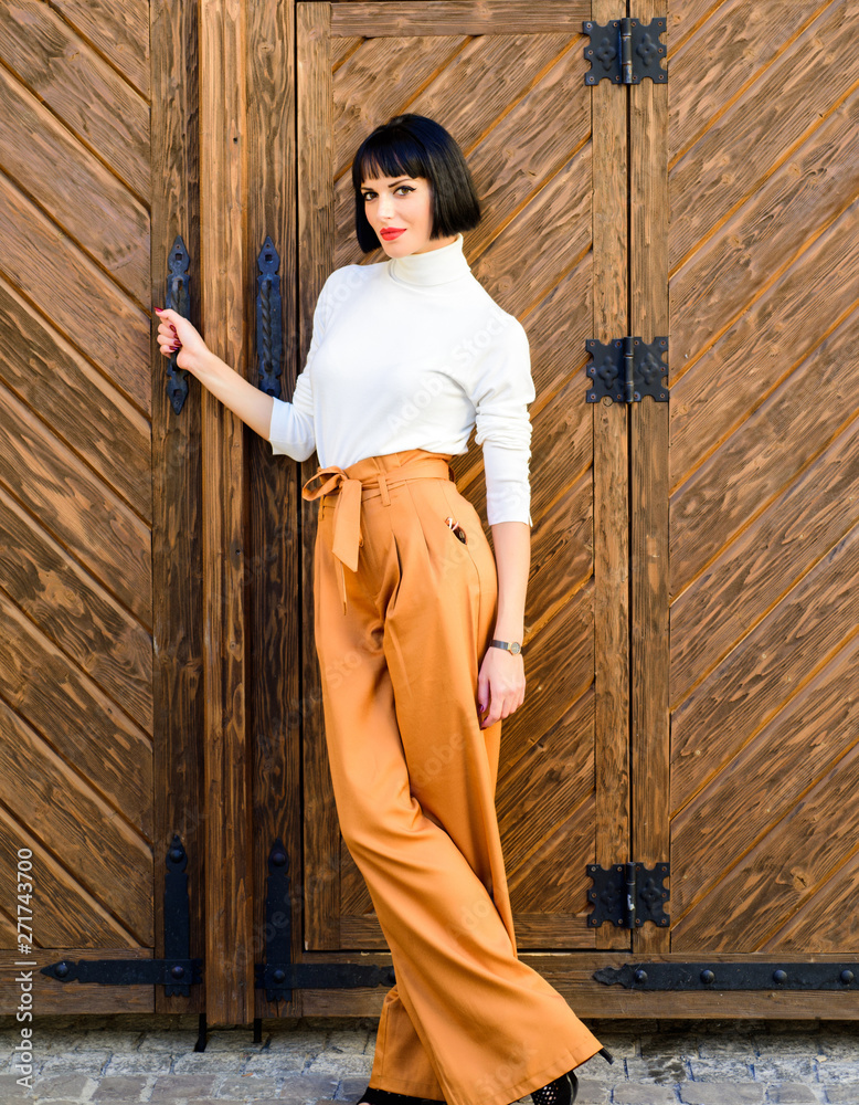 High waisted pants fashion trend. High waisted trousers. Woman attractive  brunette wear fashionable clothes. Femininity and emphasize feminine  figure. Girl wear loose high waisted pants. Fashion shop Stock Photo