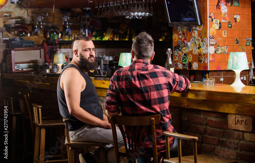 Friends relaxing in bar or pub. Hipster bearded man spend leisure with friend at bar counter. Strong alcohol drinks. Opening hours till last visitors. Friday relaxation in bar. Men relaxing at bar