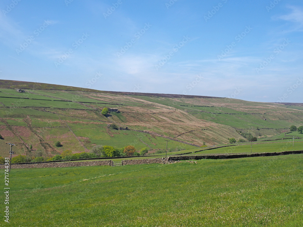 a scenic view of green meadows and stone walls underneath yorkshire hills and moorland on the old howarth road