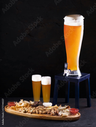 Beer set for a large group of friends. Beer in glasses closeup on the concrete table. Beer and snacks - chips, crackers and cold cuts with sauce on a wooden tray. Copy space. photo