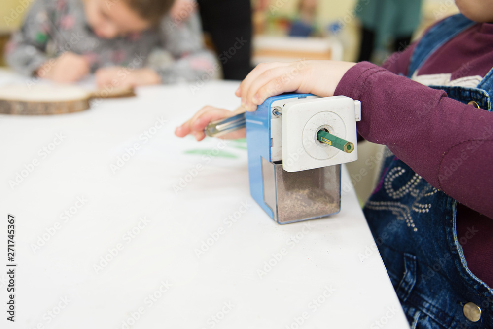 Montessori methodology school. Little girl sharpening a pencil at the