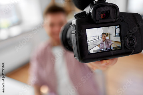 blogging, videoblog and videoblogging concept - close up of camera recording smiling male video blogger at home office © Syda Productions