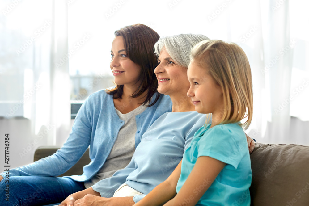 family, generation and female concept - portrait of smiling mother, daughter and grandmother sitting on sofa at home family, generation and female concept - portrait of smiling mother, daughter and grandmother sitting on sofa at home