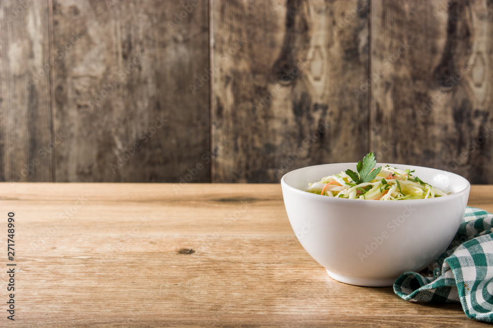 Coleslaw salad in white bowl on wooden table Coleslaw salad in white bowl on wooden table