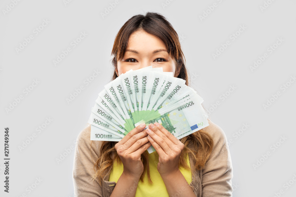people, ethnicity and portrait concept - happy asian young woman holding hundreds of euro money banknotes over grey background people, ethnicity and portrait concept - happy asian young woman holding hundreds of euro money banknotes over grey background