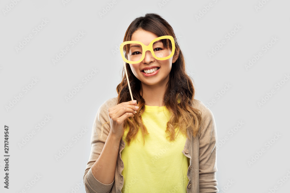party props, photo booth and people concept - happy asian young woman with big glasses over grey background party props, photo booth and people concept - happy asian young woman with big glasses over grey background
