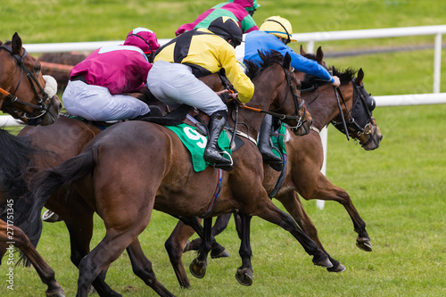 Close up on group of jockeys and race horses sprinting towards the finish line