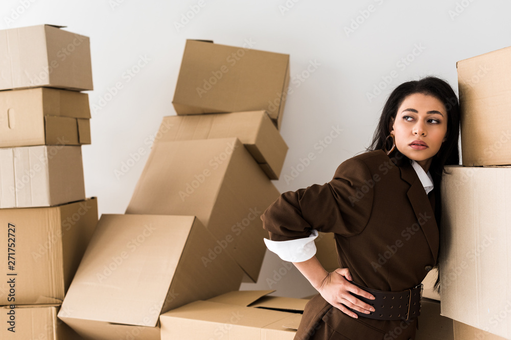 selective focus of attractive african american girl standing with hand on hip near boxes on white selective focus of attractive african american girl standing with hand on hip near boxes on white