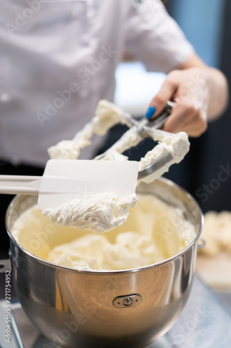 Master chef prepares a sweet dessert for the production of sweets. Mixing dough and cream for the cake in a deep bowl.