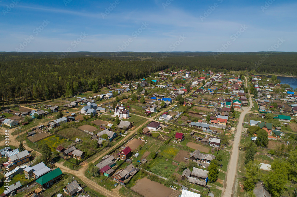 Kamenka village surrounded by forest with church in the center, Sunny day, summer, Aerial