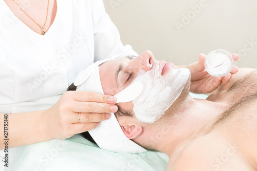 A young man is undergoing a mask treatment in a beauty salon spa. 