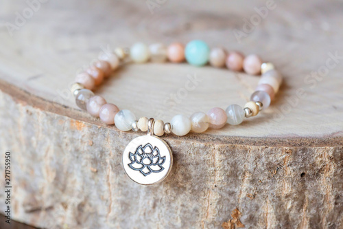 Mineral stone sun stone and lotus pendant bead bracelet on natural wooden background photo