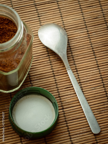 Coffee spoon lays near the jar of coffee and its cap