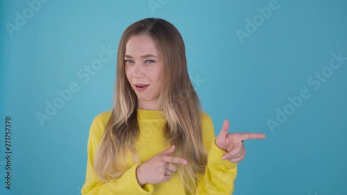 Oh yeah! this and this! Cute funny girl in a yellow sweater shows her fingers in different sides. Isolated blue background. 4K