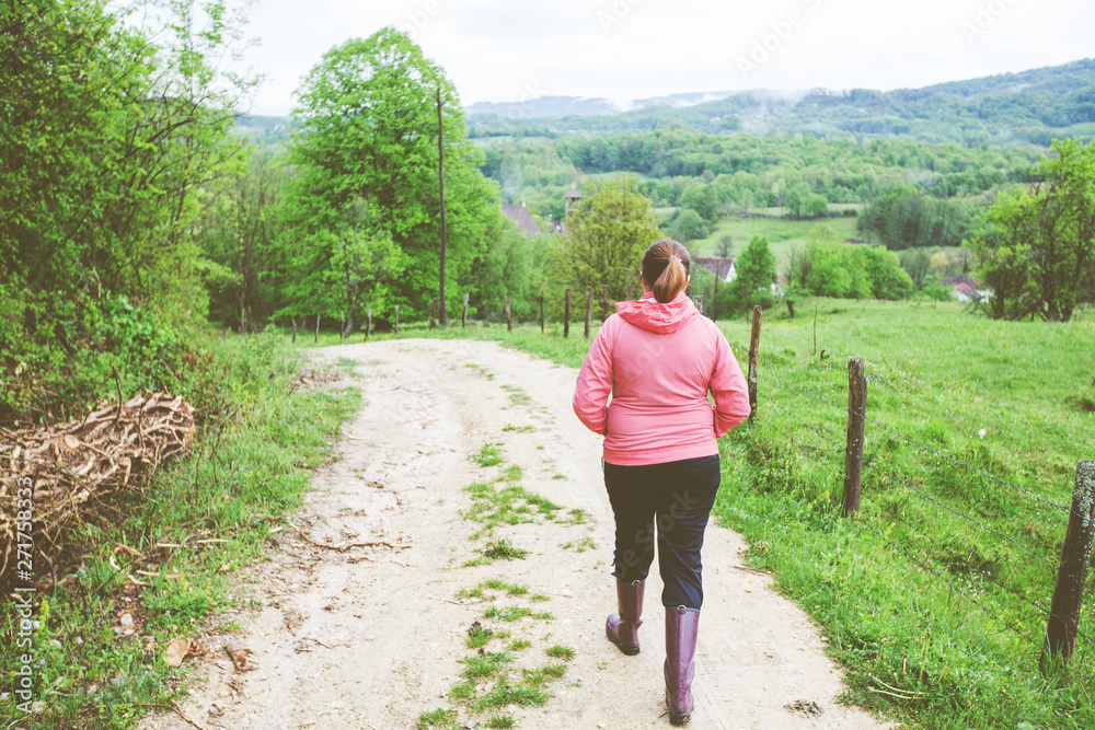 woman in rubber boots walking on rural road spring nature woman in rubber boots walking on rural road spring nature