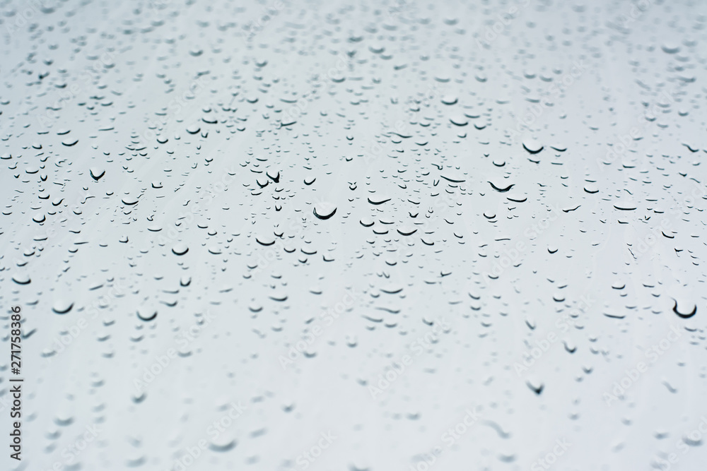 Rain drops on a window glass surface against a white background of rainy clouds. Rain drops on a window glass surface against a white background of rainy clouds.