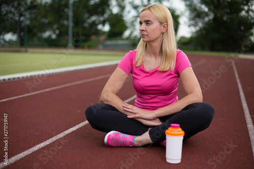 Fit girl practicing stretching exercise at stadium.Beautiful young sports woman doing exercises. A girl is training on a sports field. Young beautiful girl in sports uniform posing on sports field.