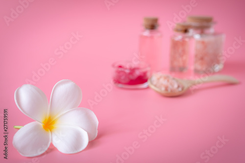 Spa wellness concept,white plumeria flower ,red candle,sea salt and rose liquid soap bottle on pink background