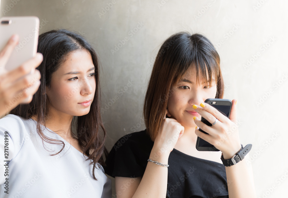 Two young asian girl using mobile phone to selfie themself