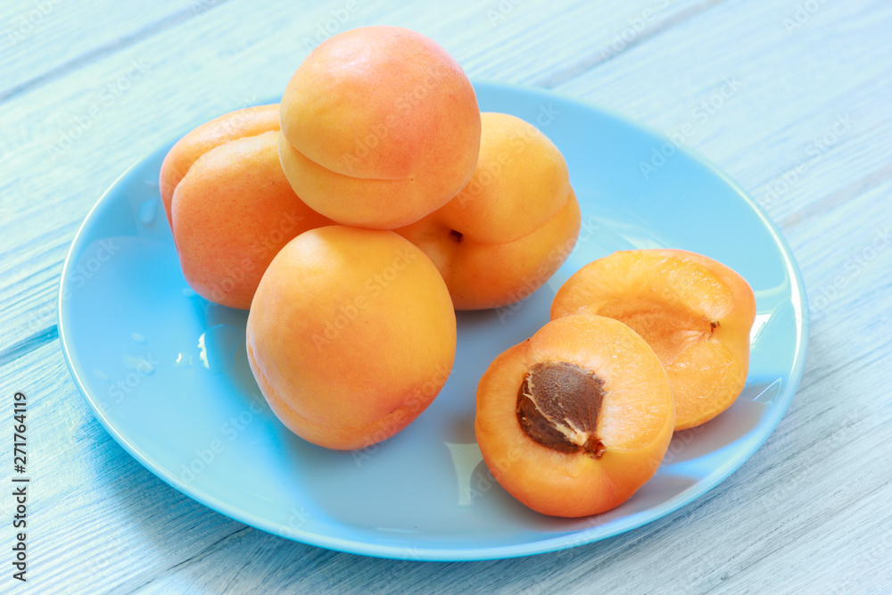 Blue plate with ripe apricots on table