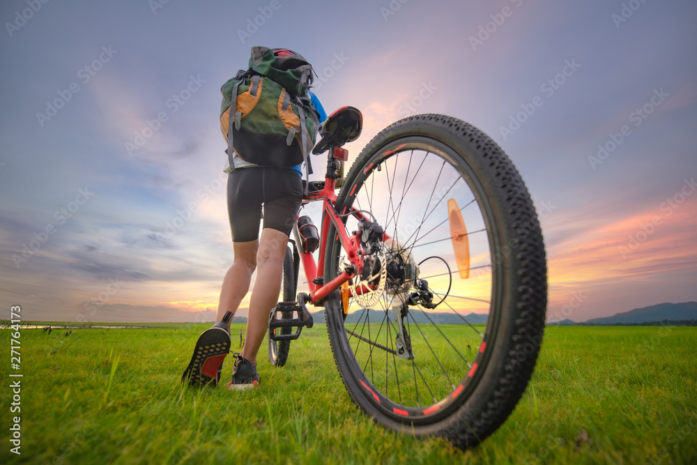 Woman cyclist bicycle riding on the way of meadow field, adventure woman riding mountain bike alone in meadow at countryside Woman cyclist bicycle riding on the way of meadow field, adventure woman riding mountain bike alone in meadow at countryside