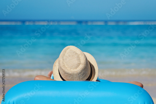 Cute European boy is enjoying his summer vacations on the seaside. He is laying on the blue inflatable floater.