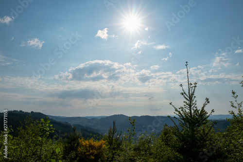 Sonne steht mit Wolken am Himmel über Bergen