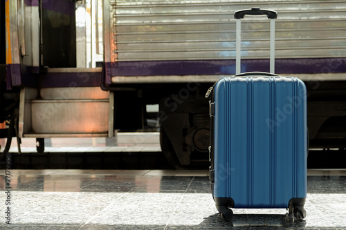 The blue suitcase is placed on the train platform.