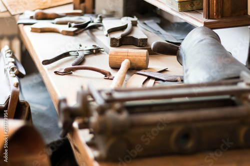A wooden mallet and other vintage leather working tools on a workbench.