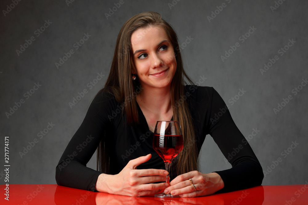 Cute girl at the red table with a glass of wine Cute girl at the red table with a glass of wine